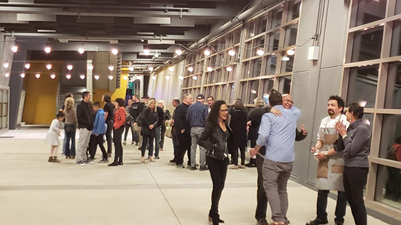 crowd of people linger in the hallway of coastline's newport beach campus during an art gallery reception