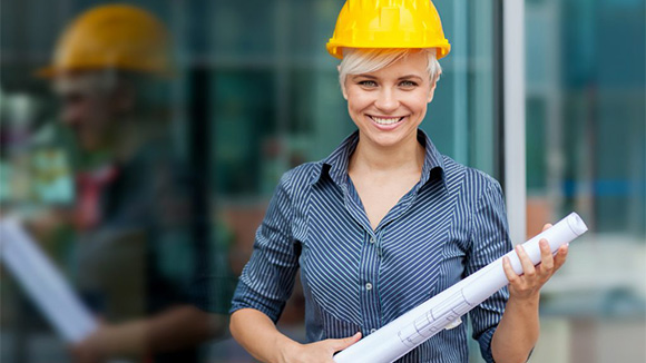 young woman wearing hardhat and holding building plans