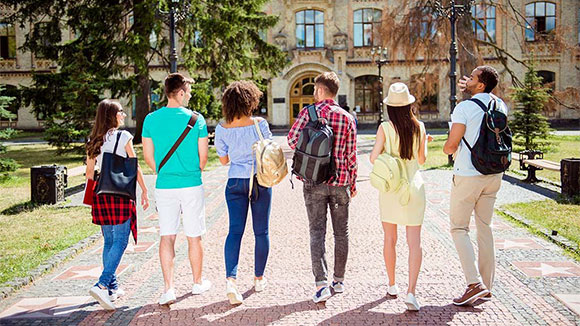 rear view of a group of students walking up to a college campus