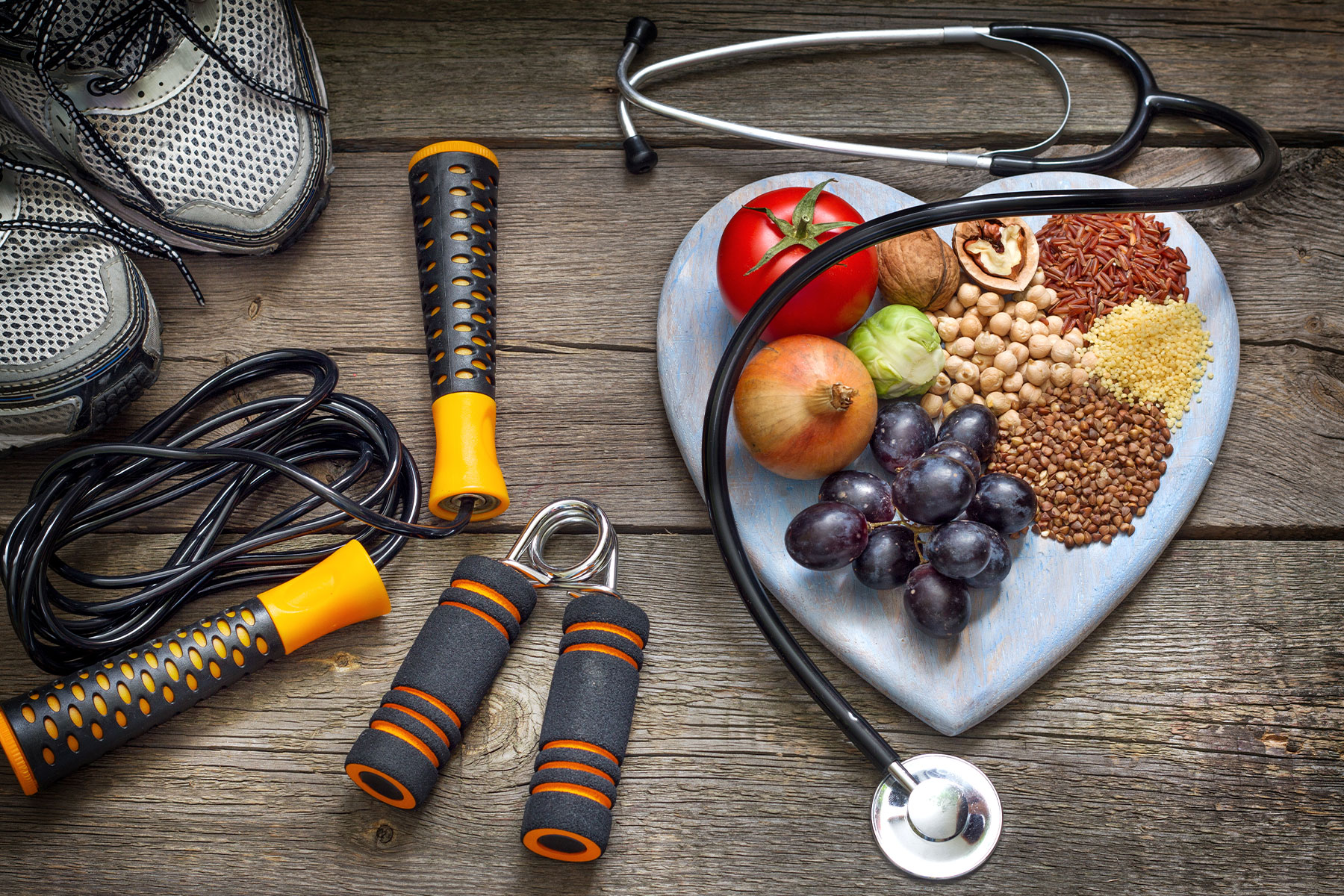 Healthy lifestyle concept with diet and fitness, heart shaped plate with healthy fruit, vegetables. and nuts sitting next to assorted workout gear