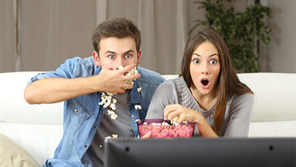 expressive couple on their couch watching a movie