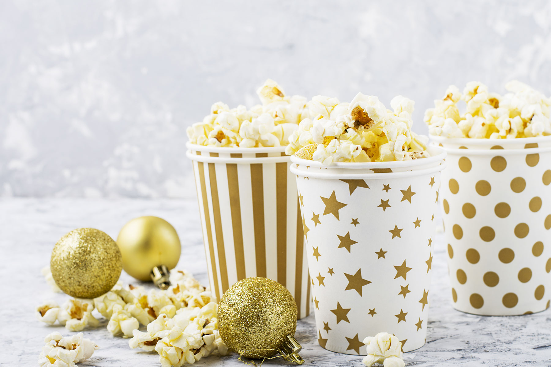 popcorn in festive white and gold cups with holiday decorations around them