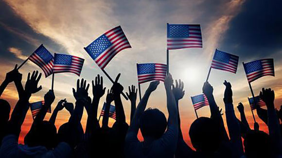 row of american flags in front of a twilight sky