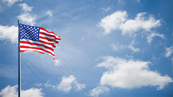 an american flag flies in front of a blue sky