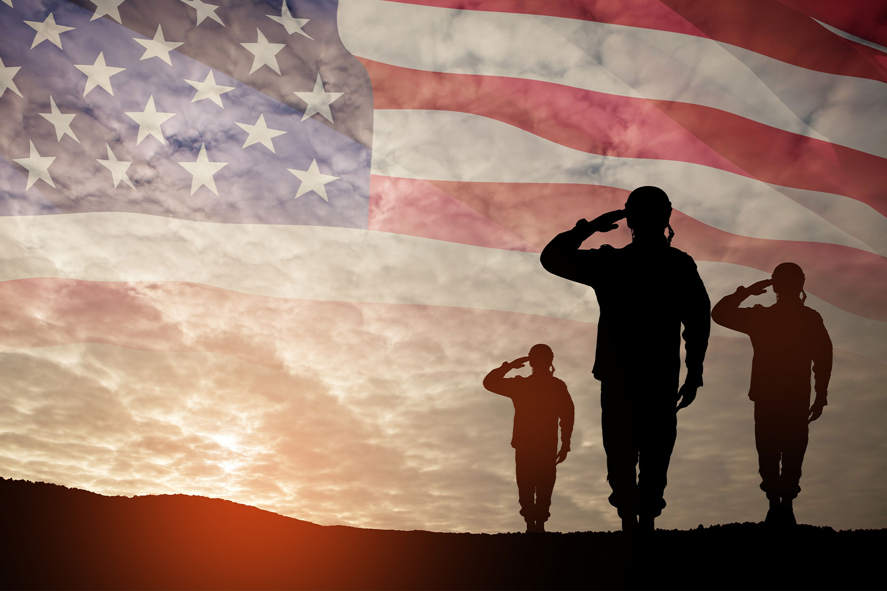 silhouettes of three soldiers saluting, flag in background