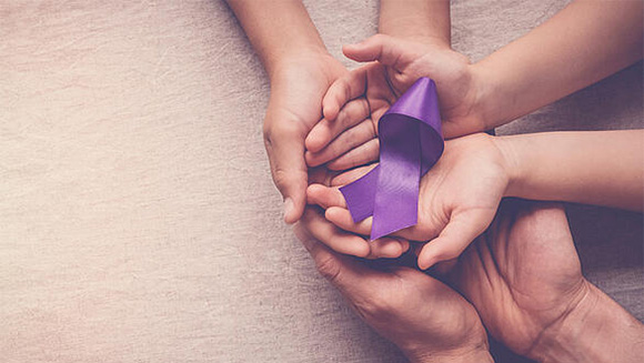 woman and young child's hands holding a purple ribbon