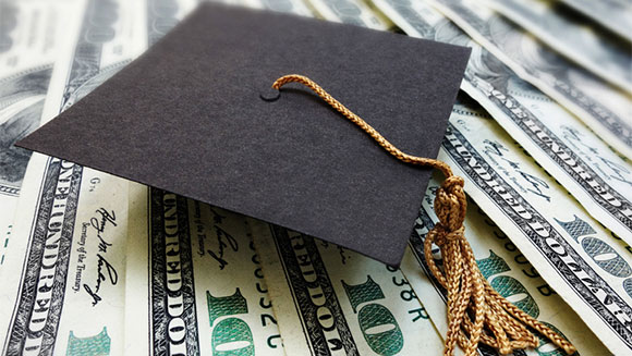 paper graduation hat resting on dollar bills