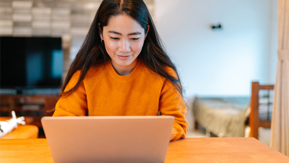 young adult woman on laptop sitting at kitchen counter