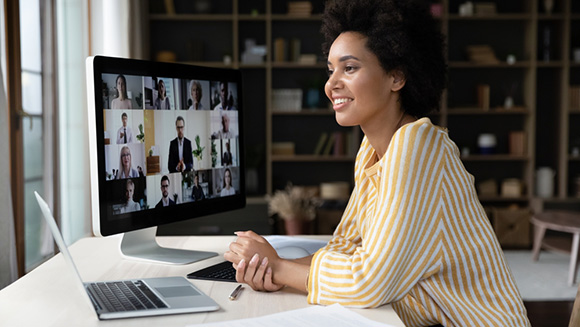 woman working on computer at home, partial view of screen showing a zoom meeting