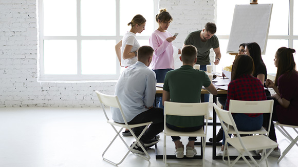 group of collegues sitting in a meeting together working on an idea board