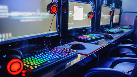close up of gaming computer with glowing keyboards, headphones, and other accessories