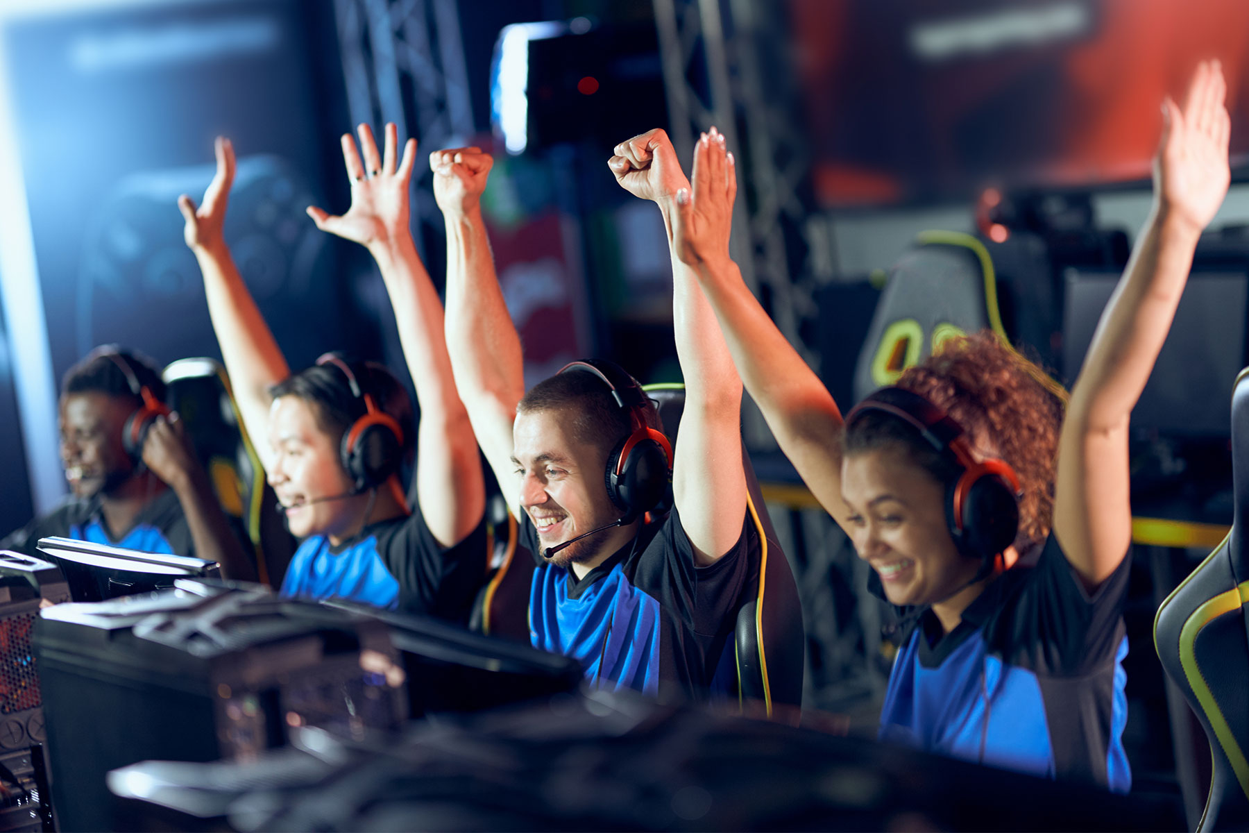 Team of happy professional cyber sport gamers celebrating success while participating in eSports tournament