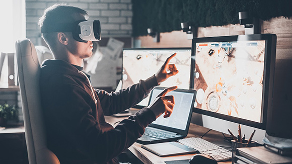 young man on computer using VR program and wearing a VR headset