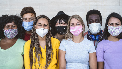 group of young friends wearing masks during covid-19 pandemic gather for photo