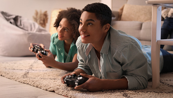 young biracial brother and sister laying on floor playing video game