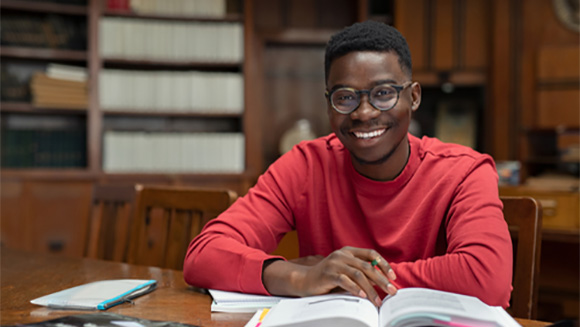 male african american student taking notes from a textbook