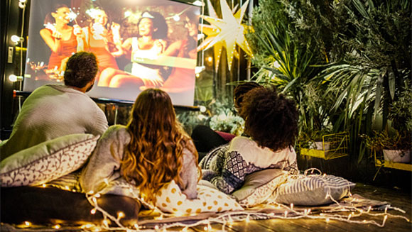 group of friends lounging in backyard about to watch a projected film