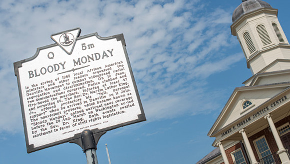 close-up of an informational plaque about Bloody Monday with the James Ingram Justice Center in the background