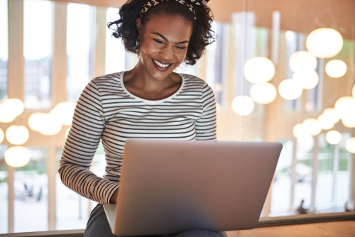 young woman smiling and working on laptop