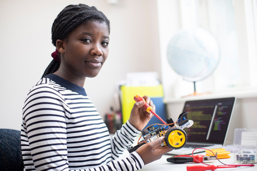 young woman working on mechanical project, holding screwdriver