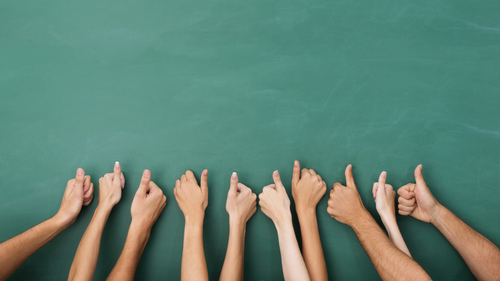 close-up of a group of arms lined up against a green background, all giving a thumbs up