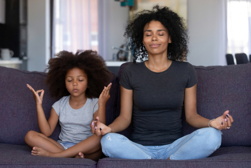 woman and daughter meditating on couch