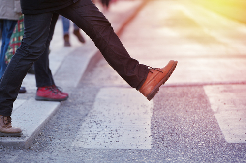 close up of man taking large step off curb