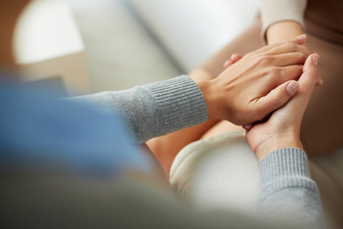 close up of someone holding another persons hand between both of theirs