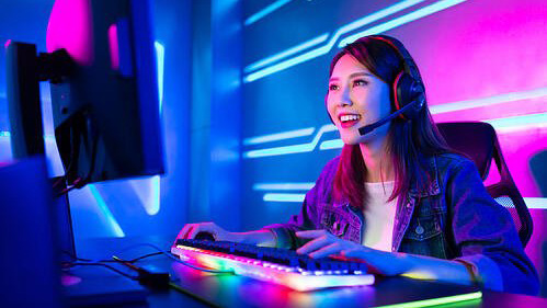 female gamer wearing headset, playing a game on PC