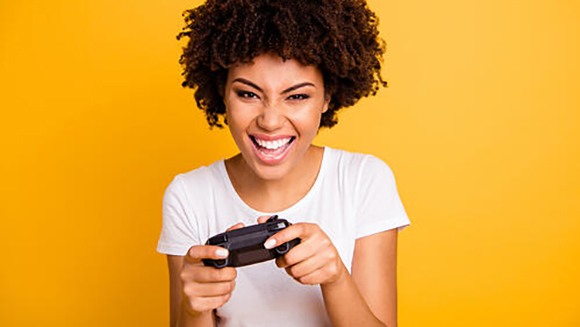 female gamer posing in front of a yellow background with a smile and holding a controller