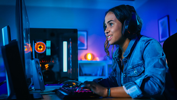 young female gamer playing a game on PC, intensly leaning over keyboard