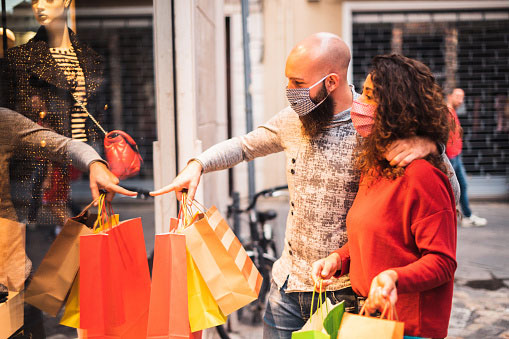 young male and female couple out shopping, wearing masks during pandemic