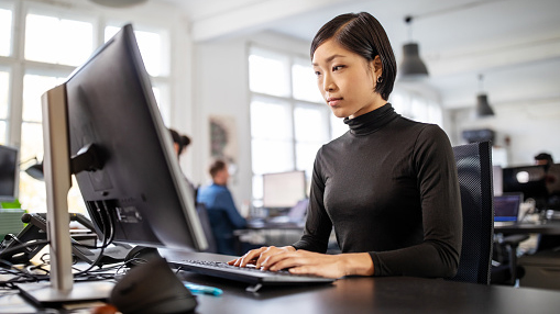 young asian woman working on a computer in a lab or office setting