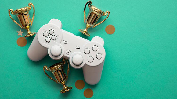 gaming control and three small toy trophys on a green background