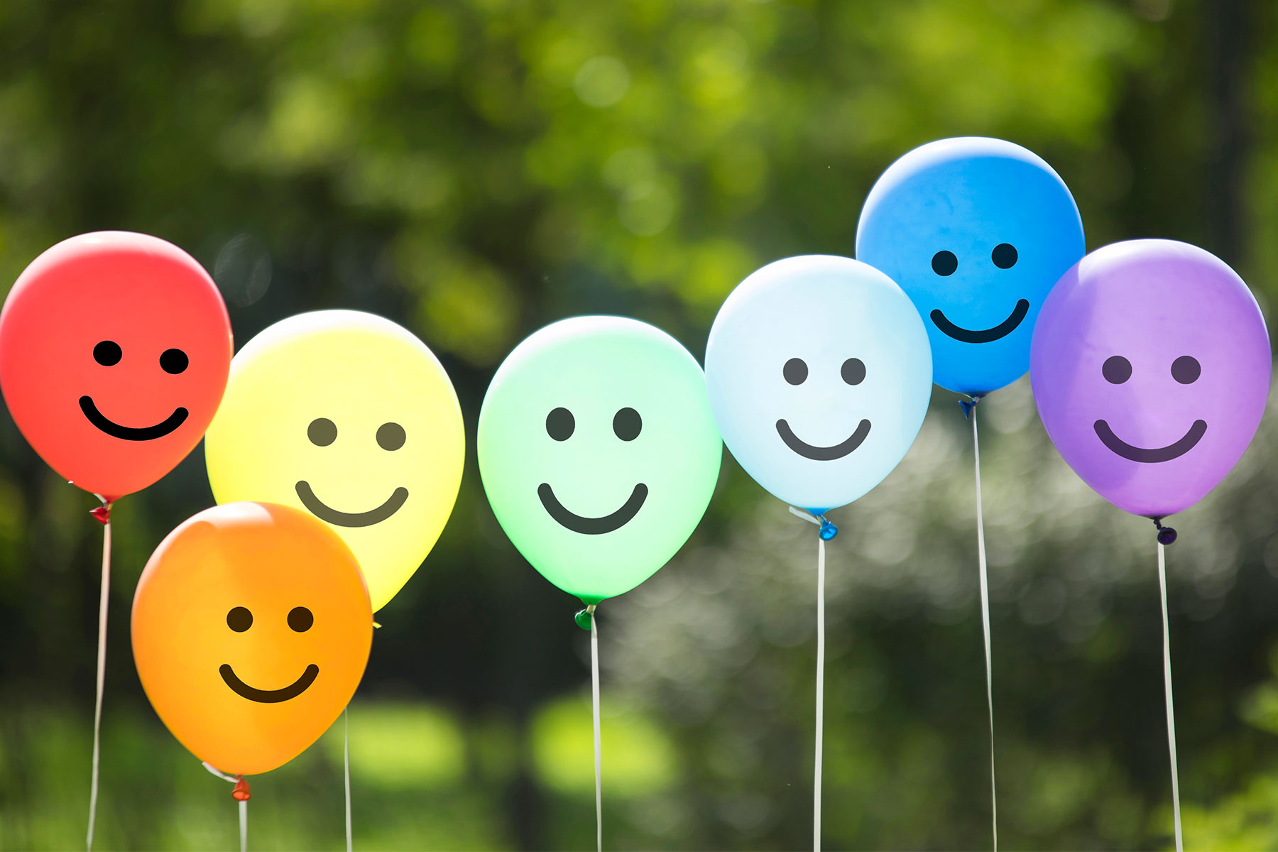 line of balloons with drawn on happiness faces in rainbow colors