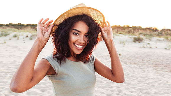 smiling woman wearing a straw hat on a beach