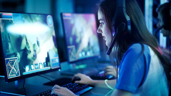 femal gamer wearing a headset playing a game on a PC computer