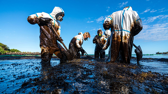 workers in hazmat gear help clean an oil spill off the coast