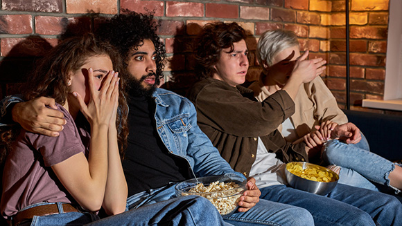 group of friends enjoying a scary movie night at home on the couch