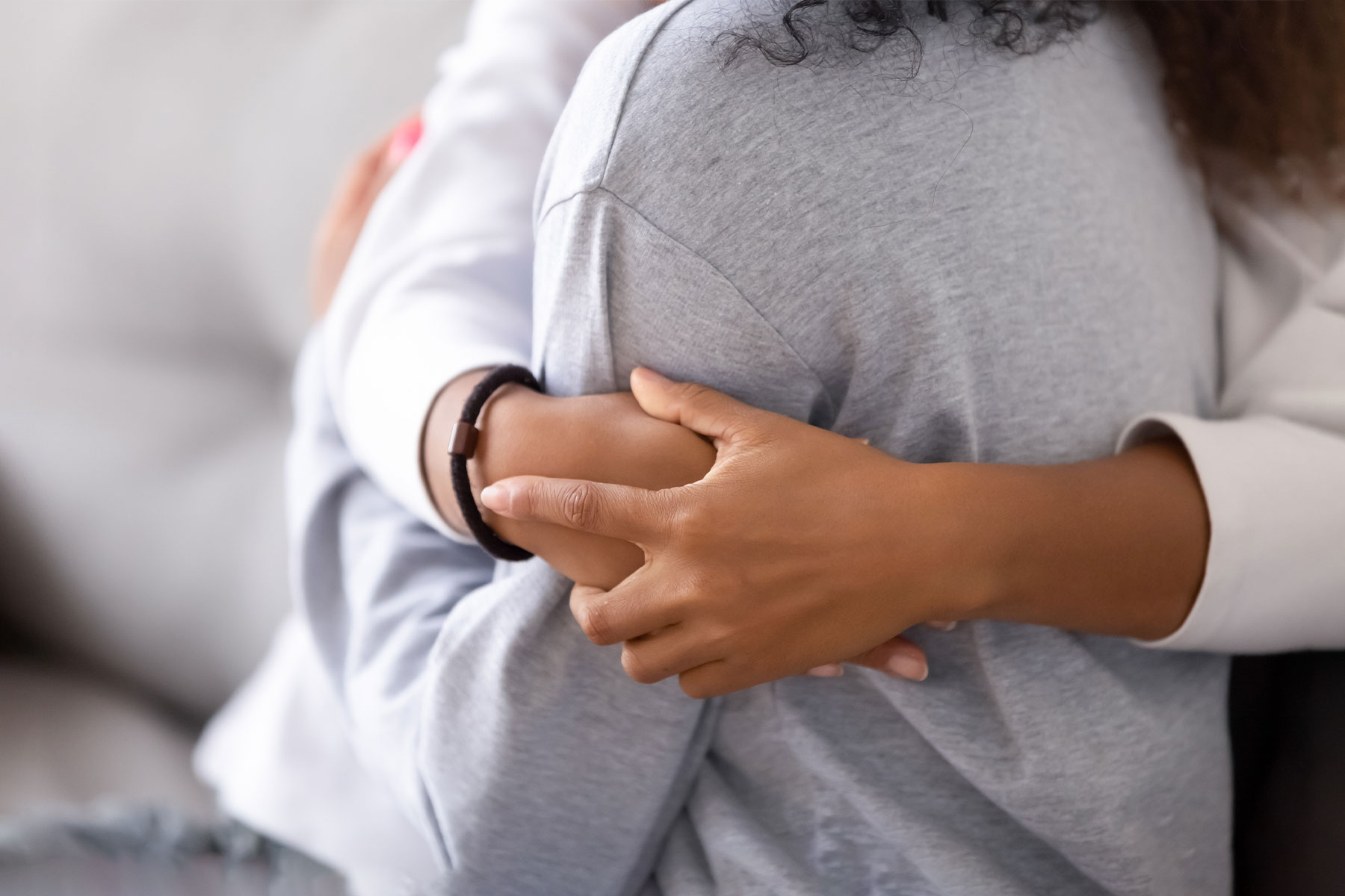 close up of linked hands as two women hug