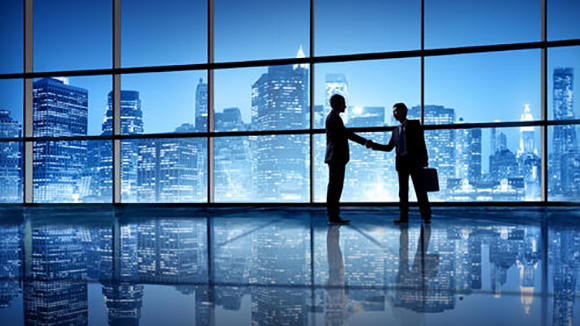 Two individuals shaking hands with the city skyline in the background