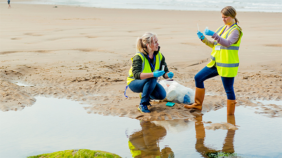 two young female biologists taking water samples from coastal waters
