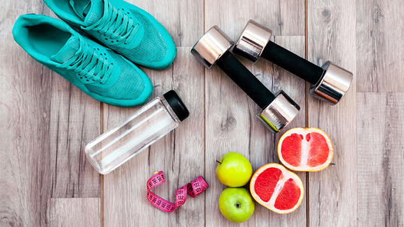overhead view of various fitness and health related items placed on a wood floor
