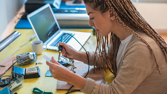 young woman soldering computer parts at desk