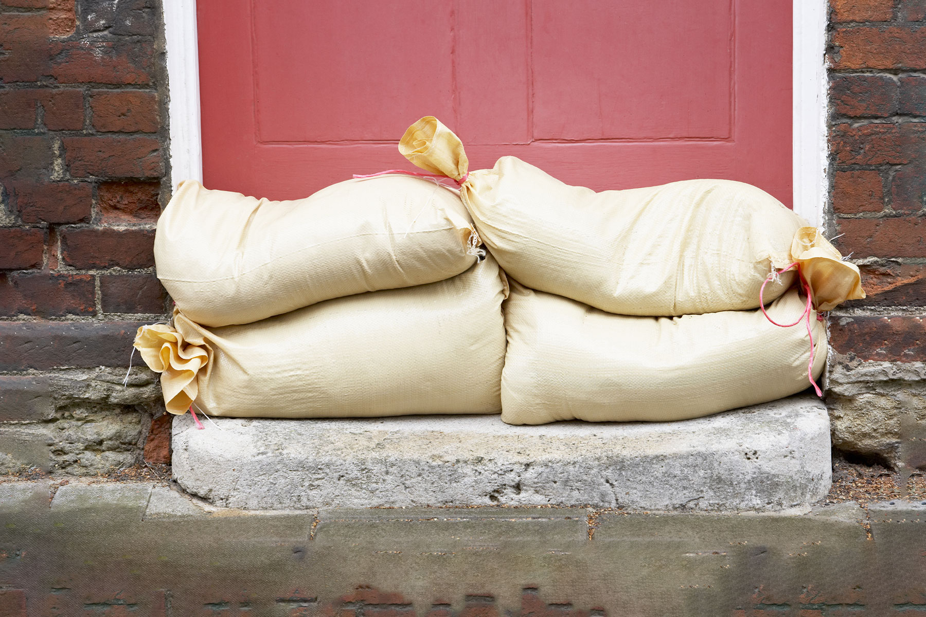 sandbags stacked in front of a red front door
