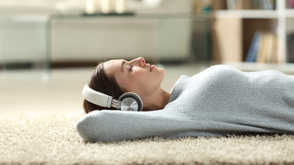 young woman resting on floor wearing headphones