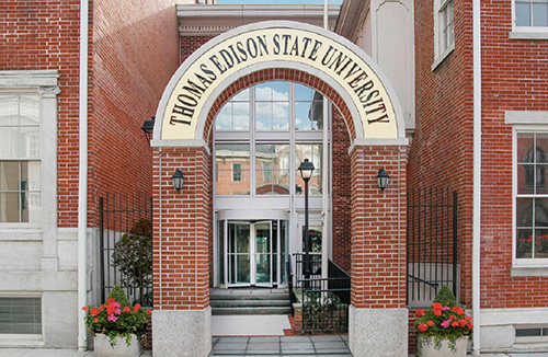 entrance to thomas edison state university, a red brick building with red brick archway and black iron gates on either side