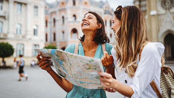 two friends laughing at possibly being lost, looking at map in what appears to be a European city