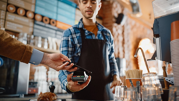 close up of a person using their cellphone to pay in a coffee shop