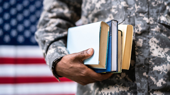 close up of student in military uniform holding an assortment of books